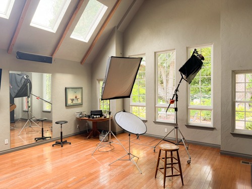Interior of the Cyr Photo studio, with a vaulted wood-beam ceiling, softbox lights and a wooden stool